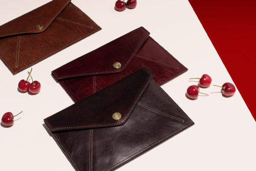 Ettore Travel Wallet in Tan, Choc and Wine next to Cherries