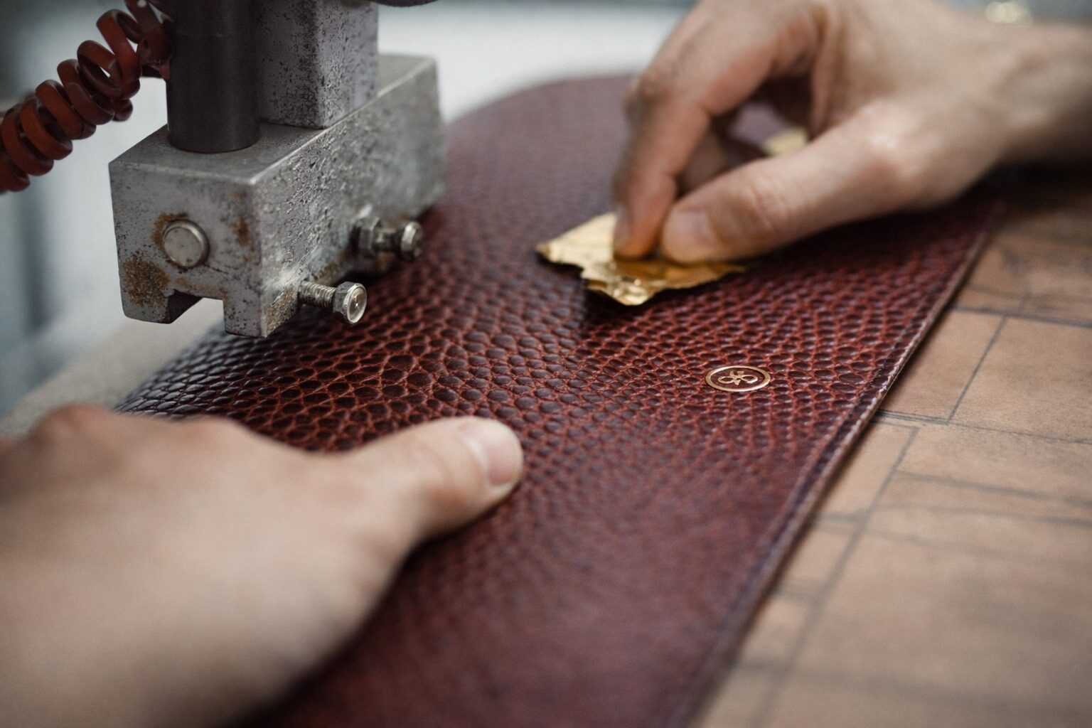 Leather embossing process showing artisan applying design to leather